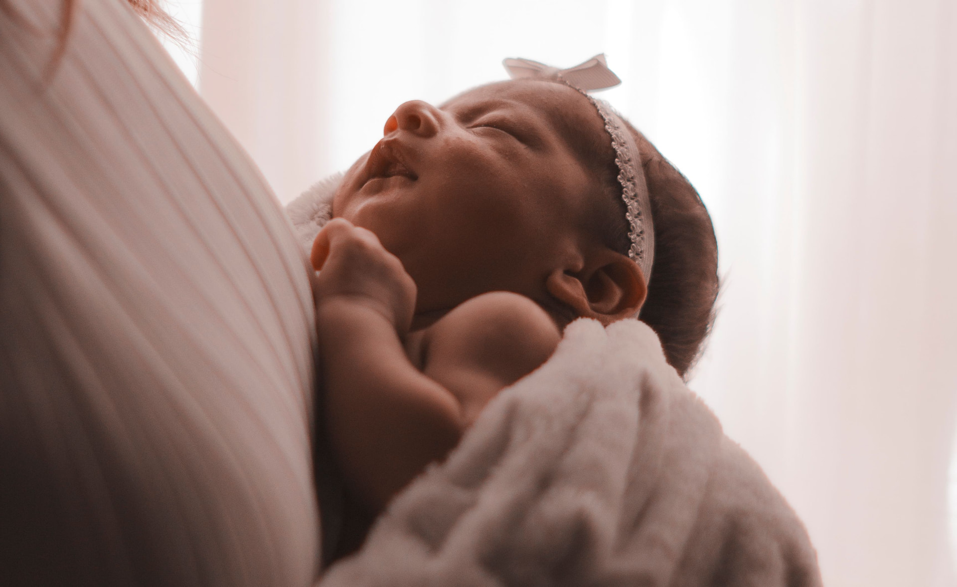 Newborn sleeping peacefully on their mother's shoulder